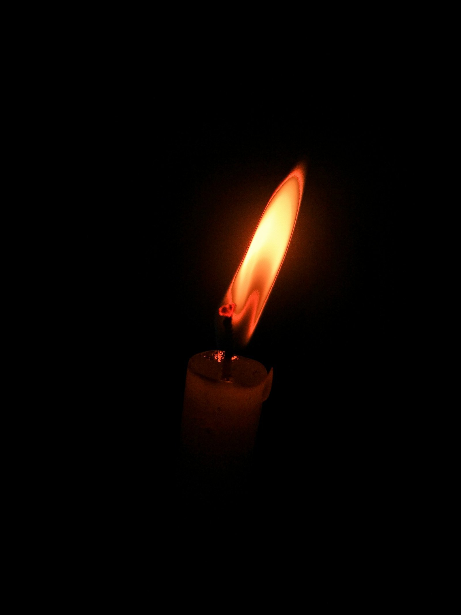 Une bougie allumée fait apparaître une petite lumière dans l’obscurité.