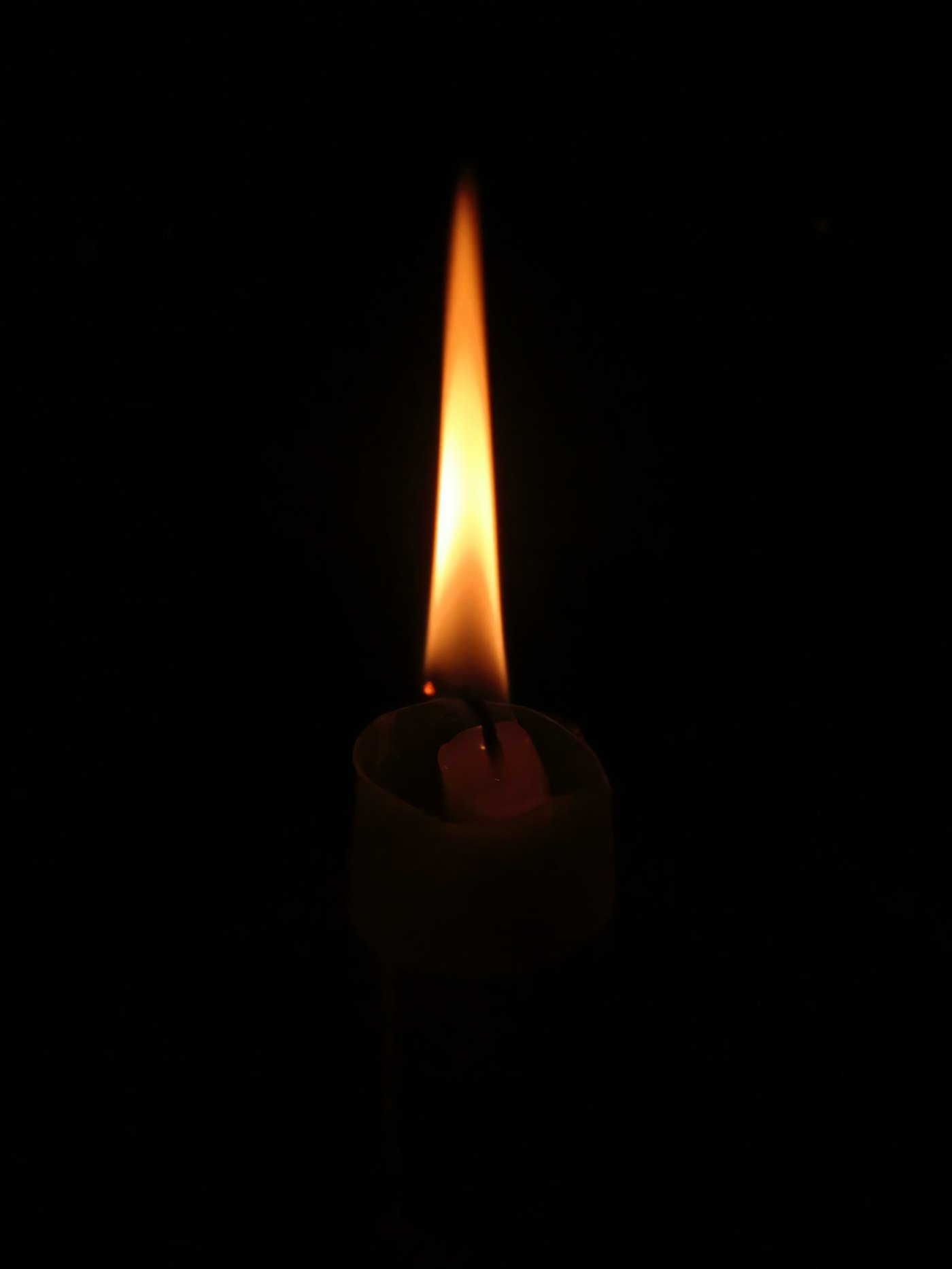 La flamme d’une bougie éclaire doucement son environnement sombre.